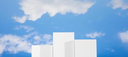 Three white geometric blocks of varying heights, resembling a podium or steps, set against a clear blue sky with white clouds, ideal for showcasing products, rankings, achievement and progress. photo