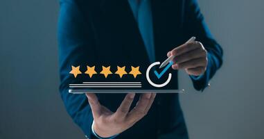 Excellent customer reviews, high service ratings, quality assurance, successful performance in business, satisfaction, Person holding a tablet displaying five golden stars and a blue checkmark. photo