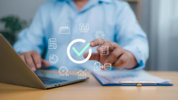 Person using a laptop with a large checkmark icon and business related icons calendar, graph, symbolizing process completion, quality assurance, efficient management, and successful project delivery. photo