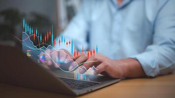 Businessman analyzing financial charts and stock market data on a laptop with candlestick graphs and digital analytics. Focus on investment, trading strategy, financial growth, decision-making. photo