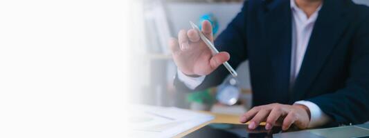 Businessman working at desk using a digital pen and tablet for data analysis, decision-making, business strategy, innovation, financial planning, productivity in a modern office with copy space. photo