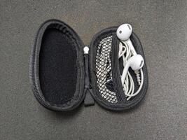 Open Earphone Case with White Earbuds on a Dark Gray Surface Closeup View photo