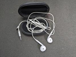 White Earphones and Black Case on Gray Surface, Isolated Overhead View photo