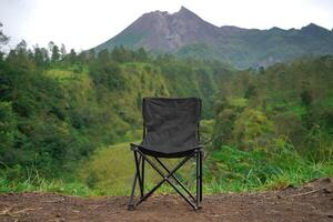 A black folding chair sitting on a dirt path photo