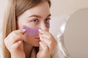 Woman Applying Hydrogel Under Eye Patches for Rejuvenation Wrinkles and Skincare Routine photo