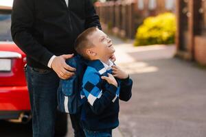 Father supports son with backpack before school, happy child looking up, first day back to school photo