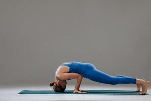 Strong woman balancing in advanced yoga arm pose showing control and flexibility in studio setting photo