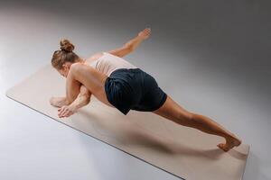 Woman practicing advanced yoga arm balance pose Eka Pada Koundinyasana on mat in studio, demonstrating core strength, balance, and flexibility in athletic wear. photo
