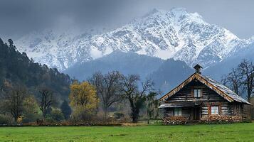A rustic log cabin nestled in a meadow with majestic snow capped mountains in the background. photo