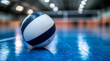 Close up of a volleyball resting on a blue court with blurred background lights. photo