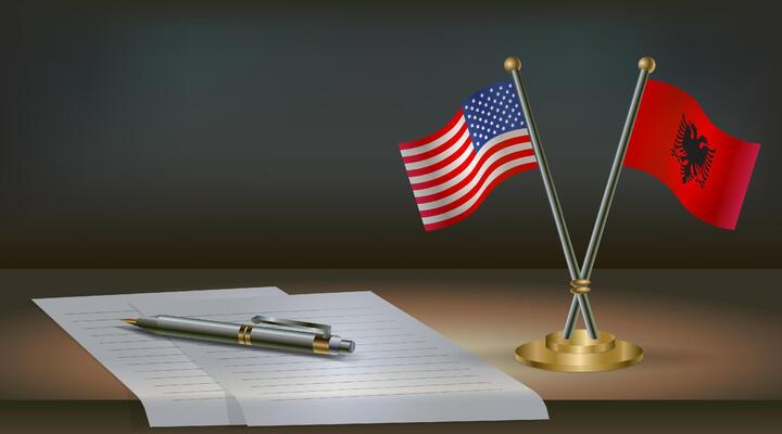 USA and Albania flags on table in office. International relations on a dark gradient color background.