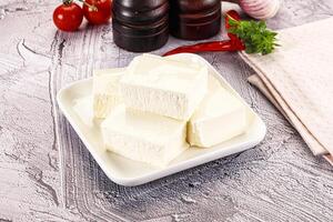 A white plate with cubes of cheese and tomatoes photo