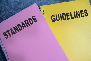 Concept of Standards and Guidelines write on book isolated on Wooden Table. photo