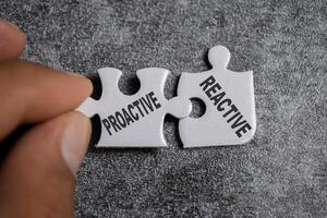 Piece of jigsaw puzzle with word Proactive and Reactive. photo