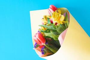 A bouquet of flowers in a paper bag on a blue background photo