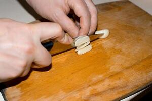 A person cutting up a piece of cheese with a knife photo
