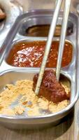 Chopsticks dip grilled meat into various sauces and powders on a dining table, highlighting Korean BBQ dining experience video