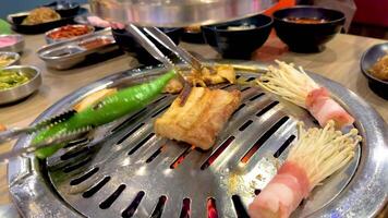 Grilled meats and vegetables sizzle on a tabletop BBQ grill in a vibrant Bangkok setting, capturing the essence of Korean cuisine video