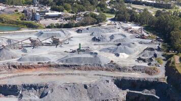 Drone footage captures active mining operations at a Gold Coast quarry, showcasing machinery, trucks, and excavators under bright daylight video