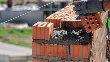 Close-Up of Mason Laying Hollow Bricks with Mortar, Precision Brickwork on Urban Construction Site video