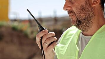 Construction Site Communication in Action, Close-up of Worker Using Walkie-Talkie Outdoors video
