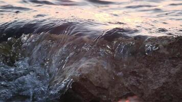 Ocean wave crashing on rock at sunset, slow motion video