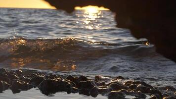 Wave against shore and sunset light, slow motion video