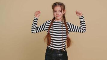 I am strong and healthy. Young cute girl showing biceps and looking confident feeling power strength to fight for rights, energy to gain success win. Preteen child kid 10 years old on beige background video