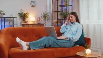 Tired young woman using laptop, suffering from headache problem tension and migraine, stress at home room. Girl working on netbook, sends messages, makes online purchases, watching movies. Lifestyles. video