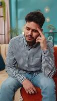 retrato do triste indiano homem cara senta às casa parece pensativo pensa sobre vida preocupações ou não correspondido amor sofre a partir de Injusto situação. problema pausa acima depressivo sentindo-me mau irritado esgotamento. vertical video