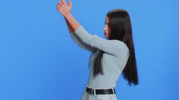 Caucasian young woman pointing around with finger gun gesture, looking confident, making choice shooting killing with hand pistol right on target. Girl isolated alone on blue background. Advertisement video