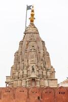 Ancient shikhara temple tower rising above red wall in Jaipur, India photo