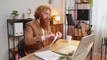Caucasian redhead businessman opening envelope reading bad news in letter feels upset sitting at home office desk. Financial problems, bank debt bill for pay, tax invoice or bankruptcy notification. video