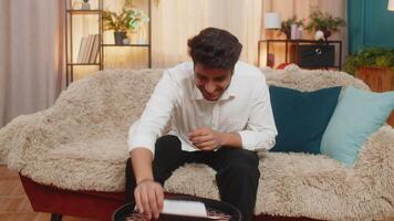 Indian man at home reading a letter with great news, celebrating a job offer, positive test results, or lottery win. Arabian guy expressing joy and excitement, celebrating success with a big smile video