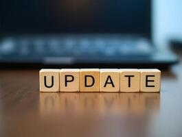 Wooden cubes showing update on a shiny surface with laptop background photo
