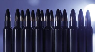 Perfectly aligned row of polished chrome rifle cartridges with dark lead bullet tips photo
