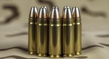 Seven .45 caliber ammunition rounds standing upright on camouflage fabric photo
