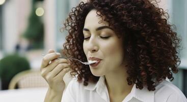 Close up of a woman with curly hair savoring a delicious dessert outdoors photo