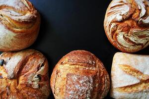 Assortment of fresh bread on black background. Freshly baked homemade bread loaf on rustic dark background photo