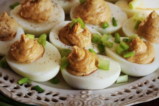 Deviled eggs with cod livers with leek on white plate. photo