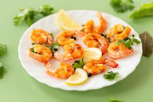 Hot shrimps with citrus slices and spices in a plate isolated on green photo