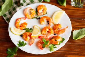 Delicious sea shrimps with lemon in a plate on a wooden photo