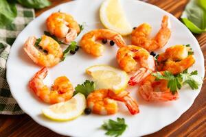 Fried juicy shrimps in a plate on a wooden photo