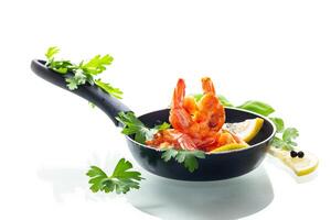 Hot shrimps with citrus slices and spices in a frying pan isolated on white photo