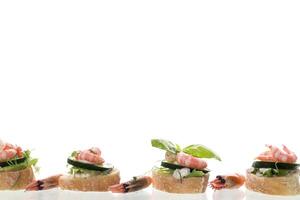 Minimalistic canapes with shrimps, salad and cucumber on a white background photo