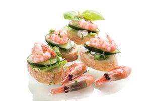 Appetizing appetizers with shrimps, sauce and cucumbers on a white background photo
