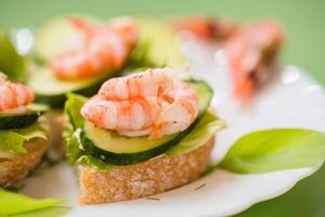 Portioned appetizers with shrimps, lettuce and sauce isolated on a green background photo