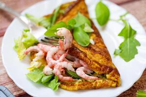 Fried omelette with shrimps and greens on a wooden table photo