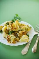Fried cauliflower with spices and herbs on a green background . photo