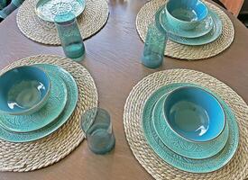 Blue dishes on table, plates and glasses, plates on wicker coasters, top view photo